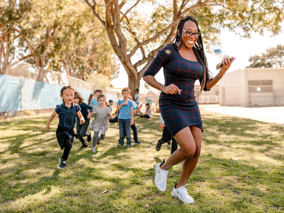 woman in dark dress being chased by young children