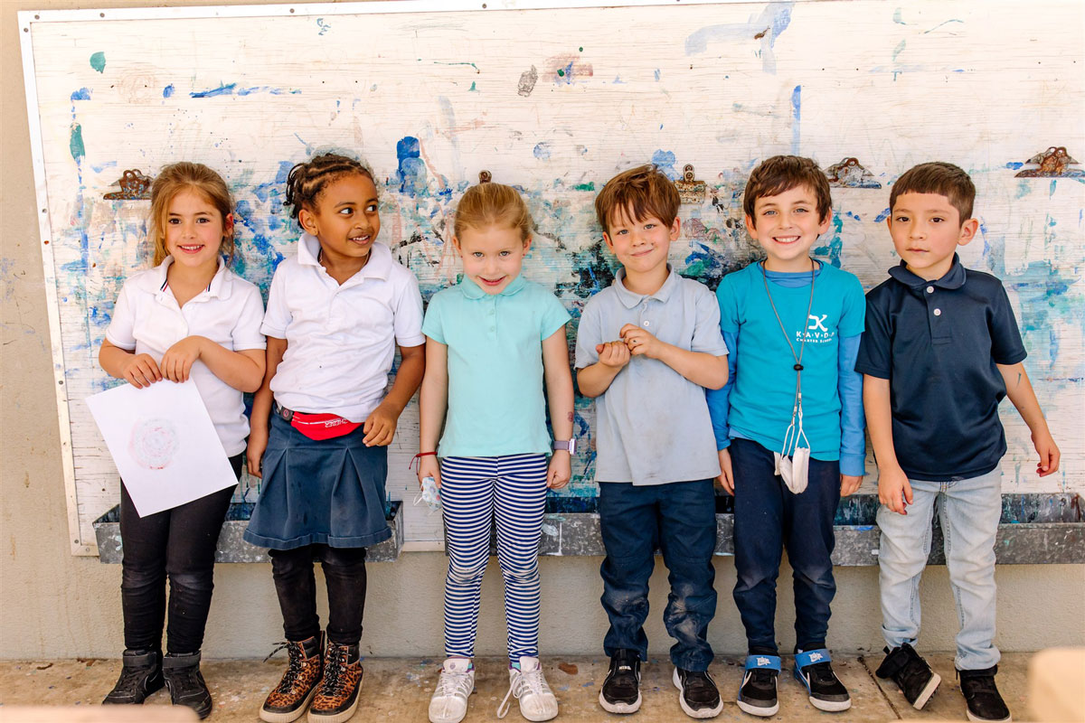 Kavod Charter School students stand in a line against a colorful wall