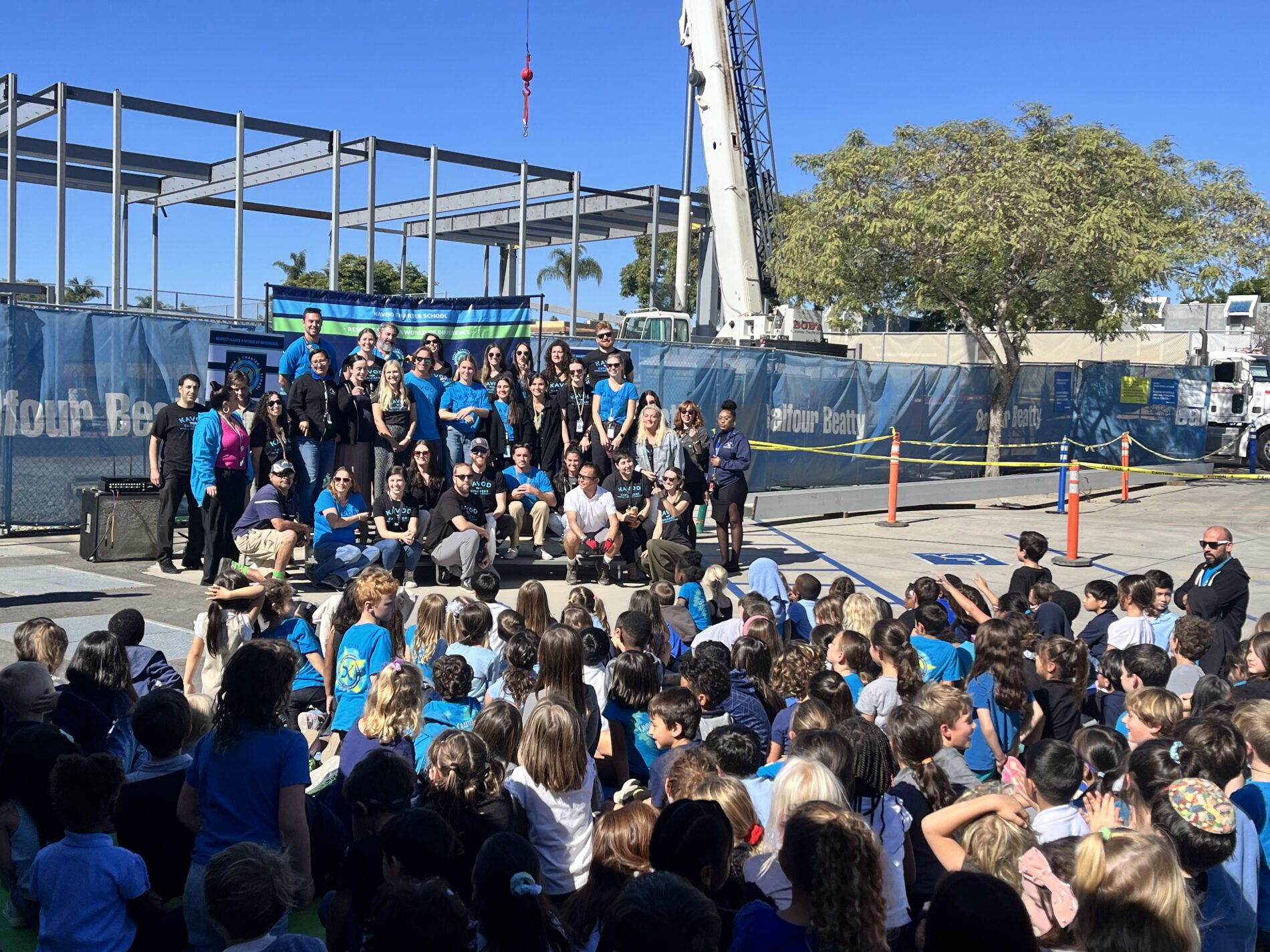 Kavod students sit together facing the expansion project while community members gather for a photo during the Beam Signing Ceremony. 