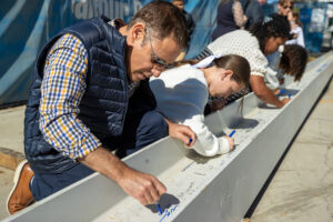 Community members signing a beam during Kavod’s Beam Signing Ceremony.