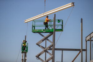 Construction workers raising the beam up to be set into the new Multipurpose building that will house a full gymnasium and theater.