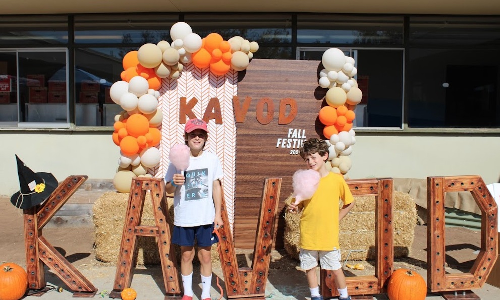 Kavod explorers pose with their cotton candy in front of a Kavod backdrop during the Fall Festival. 