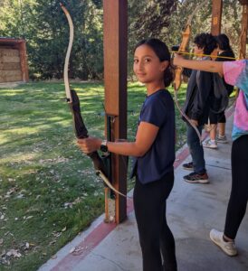 A Kavod middle schooler holding a bow, practices archery during an after school archery club.