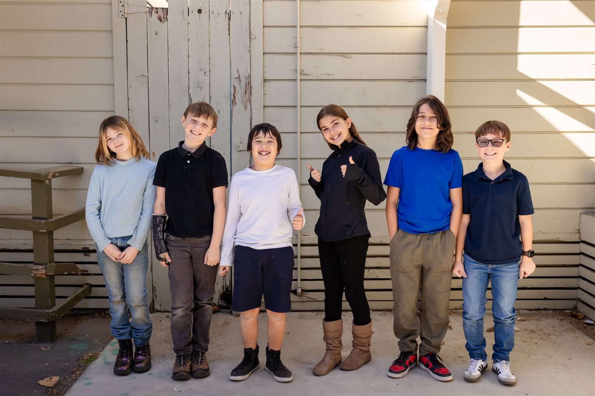 A group of Kavod Charter School students gather outside and smile at the camera.