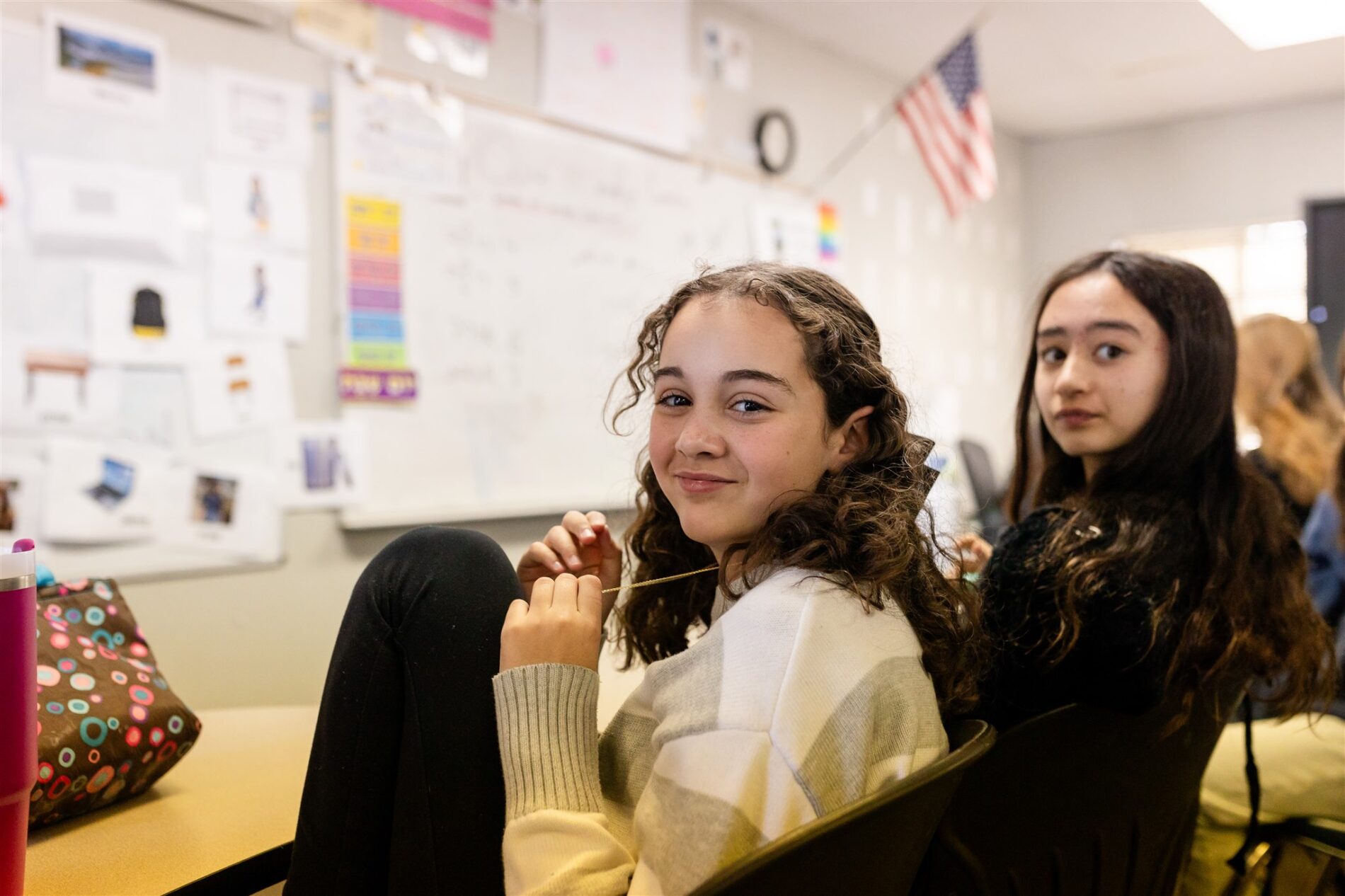 Two Kavod Charter School students in a classroom turn their heads to look back at the camera.