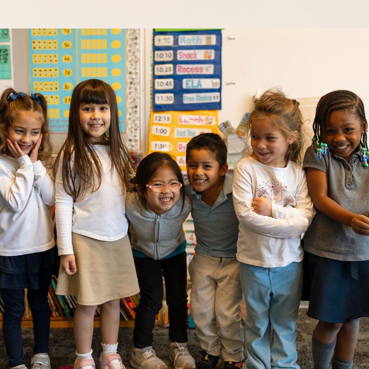 A group of Kavod students smiling together in their classroom.