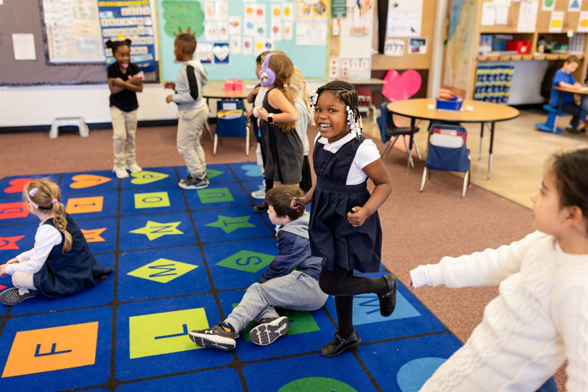 Kavod kindergarteners dance together on the classroom carpet.