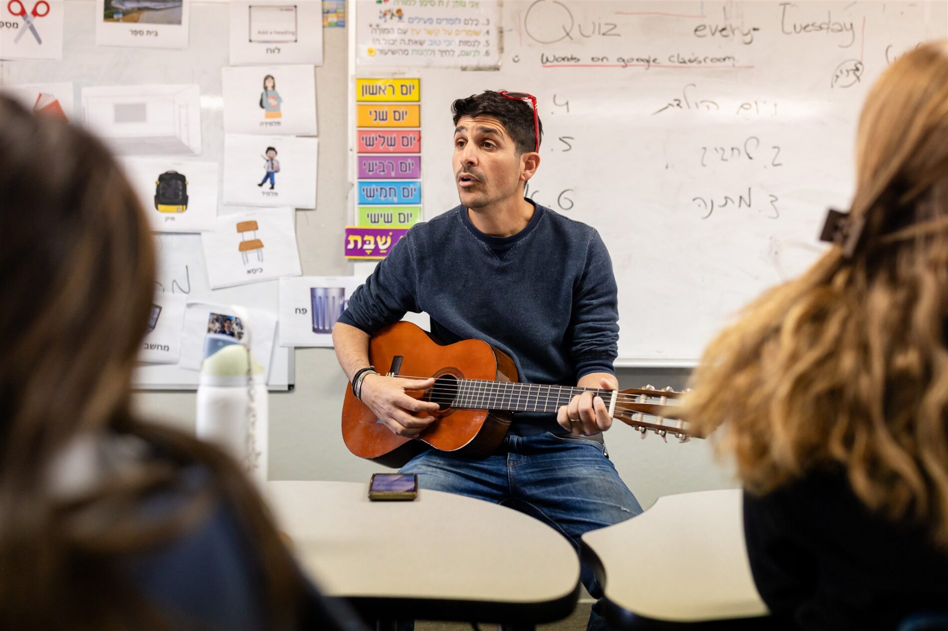 A Kavod Charter School teacher is playing the guitar in a classroom.